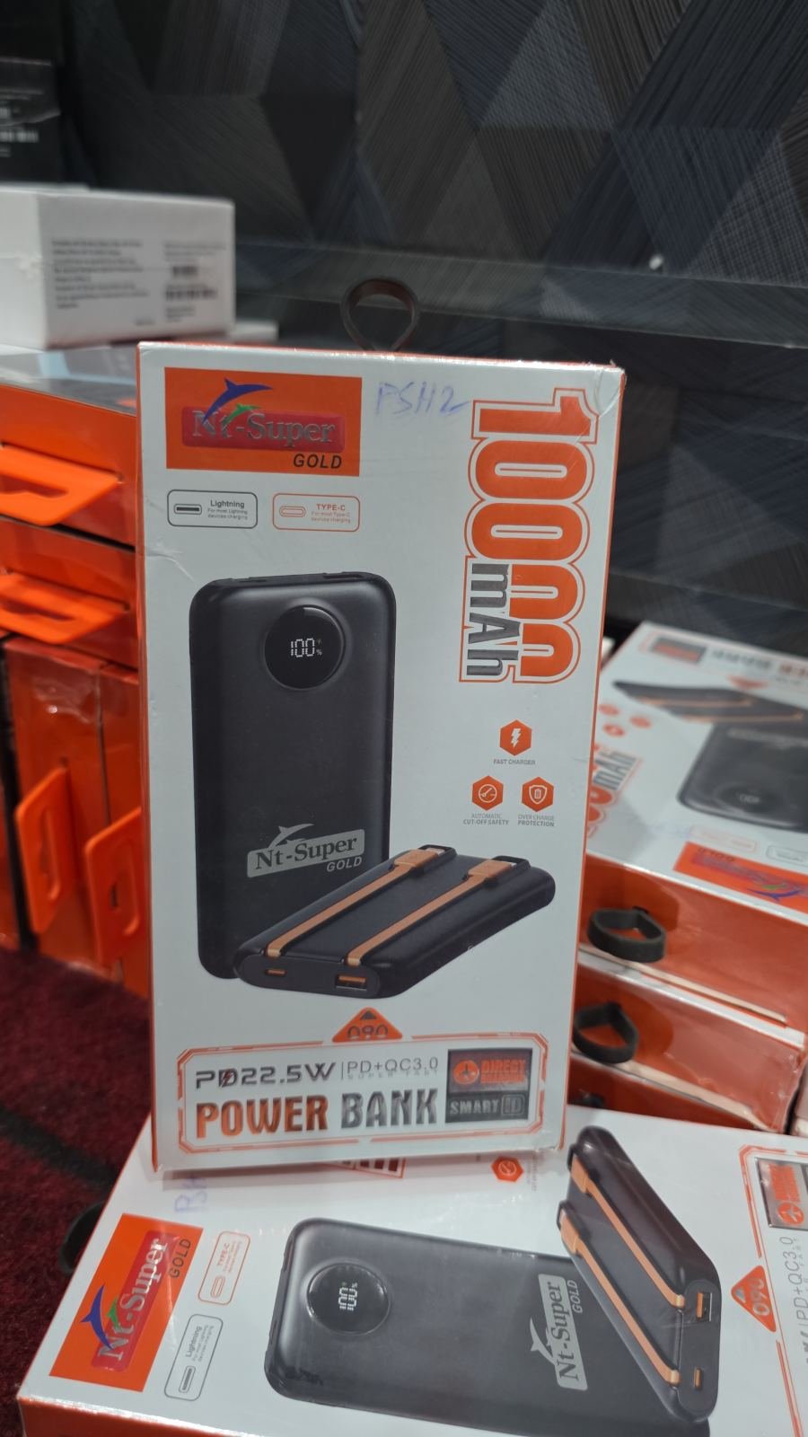 NT Super Gold 10000 mAh Power Bank packaging box featuring a black portable charger with built-in charging cables and a digital percentage display